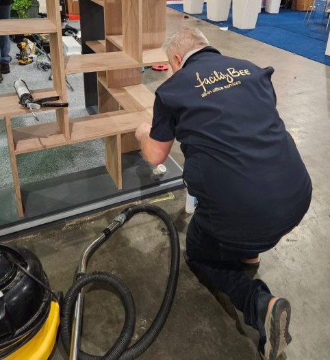 FacilityBee-medewerker die een houten meubel opbouwt op een evenementenlocatie
